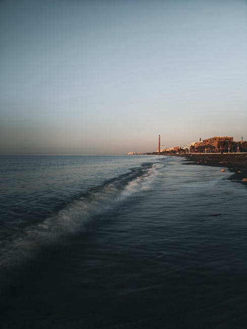 Vista del mar al atardecer con edificios en la costa.