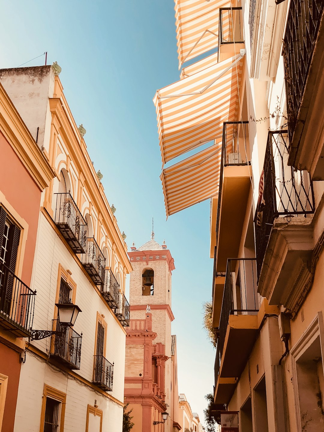 Vista de una calle con edificios y toldos en Sevilla.
