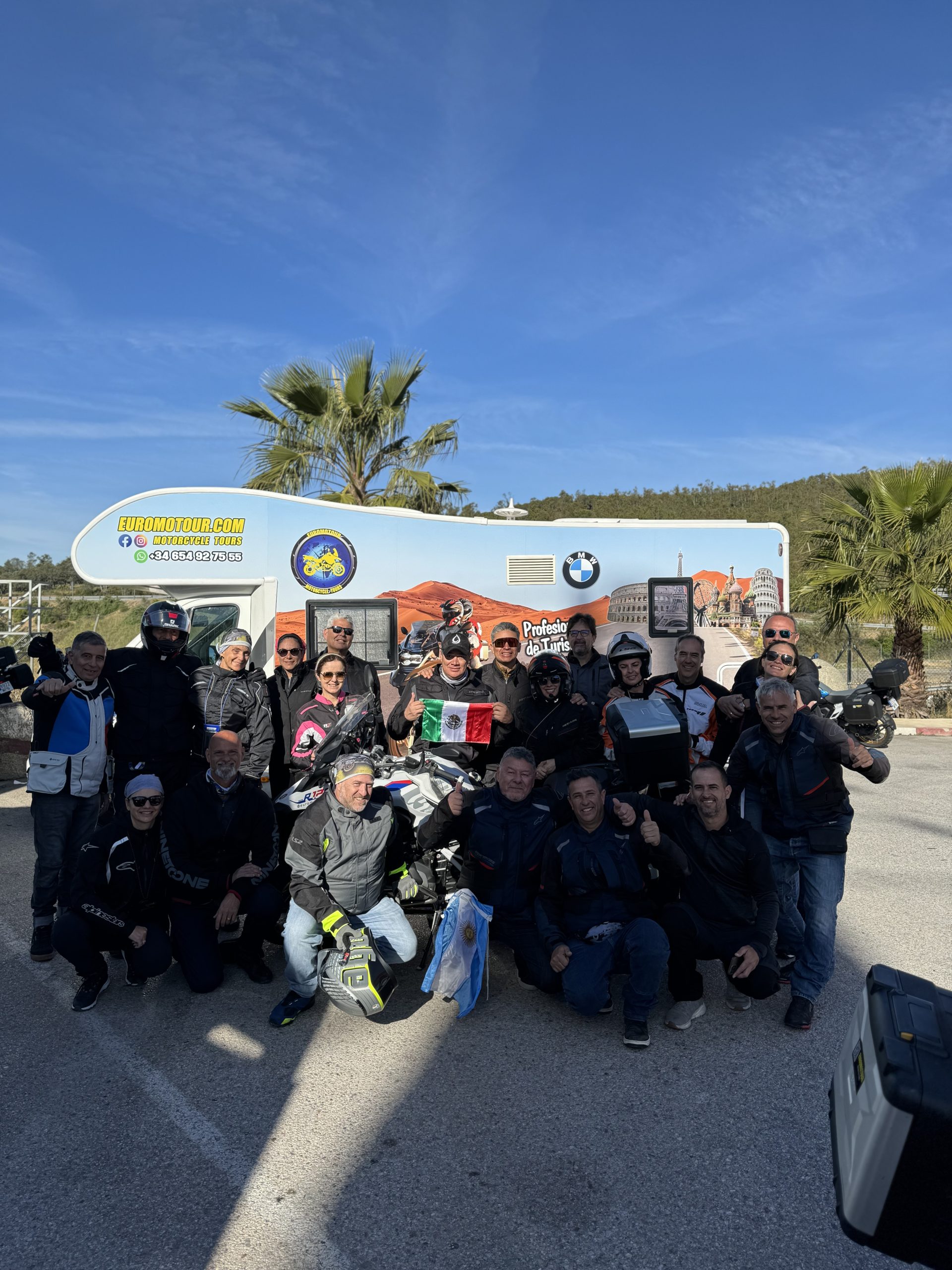 Grupo de motociclistas posando frente al vehículo de la caravana.