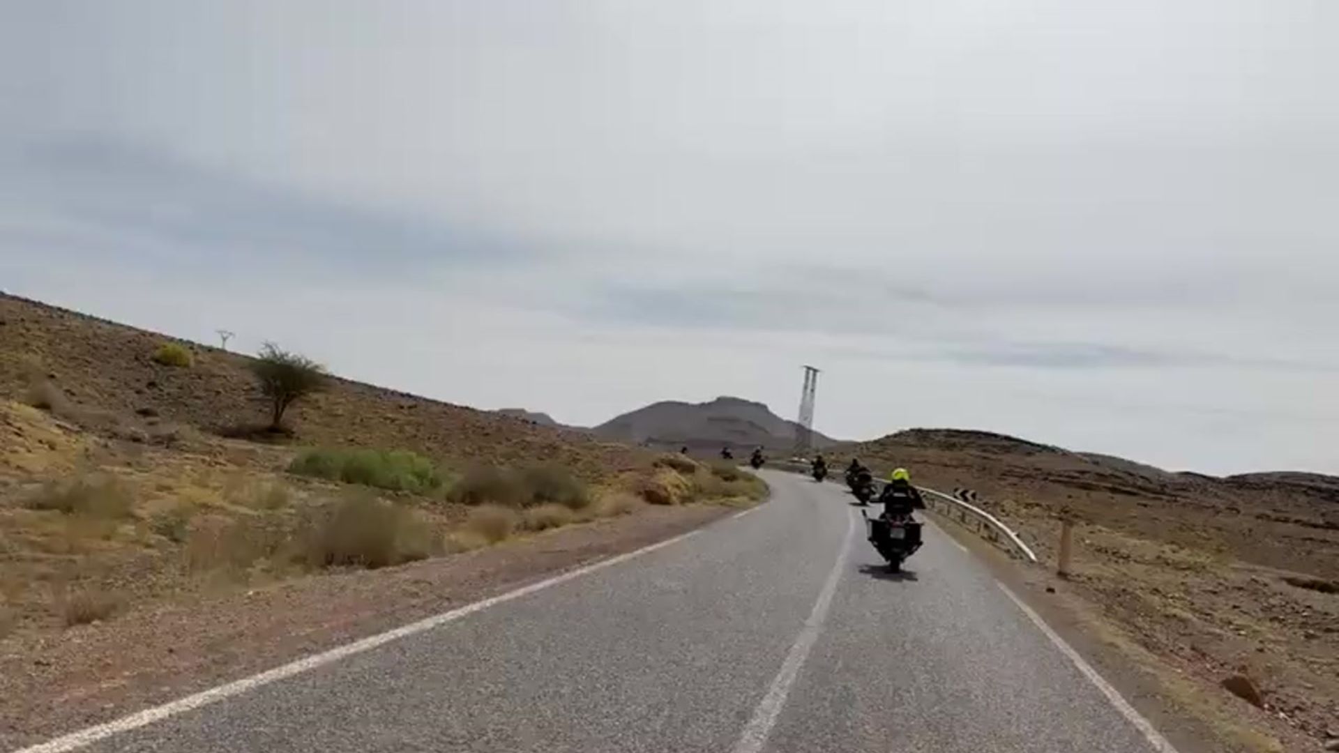 Convoy de motociclistas en carretera con vehículo de apoyo en ruta.